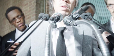 a group of people standing behind microphones in front of a brick wall