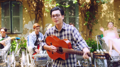 a man holding a red guitar in front of a group of people