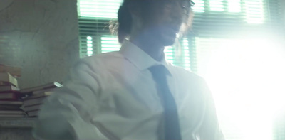 a man in a white shirt and tie standing in front of a stack of books