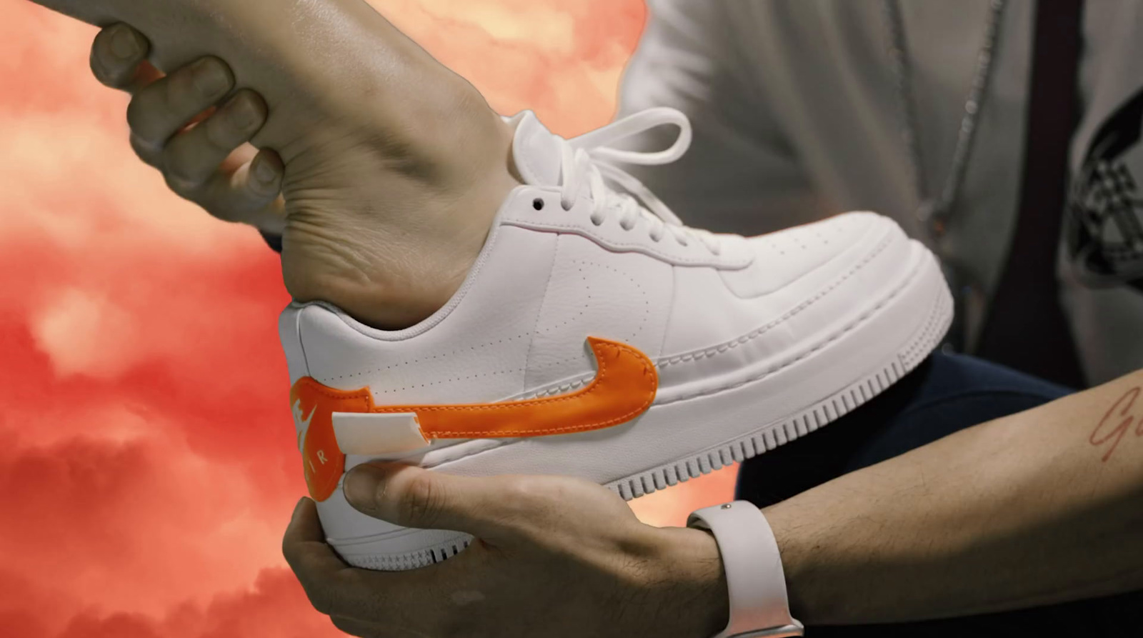 a person holding a pair of white and orange sneakers