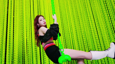 a woman on a rope in front of a green wall