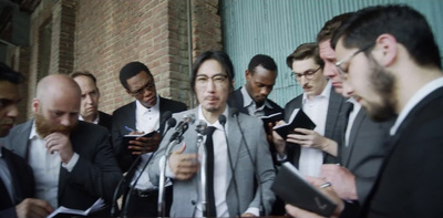 a group of men standing around each other in front of a microphone