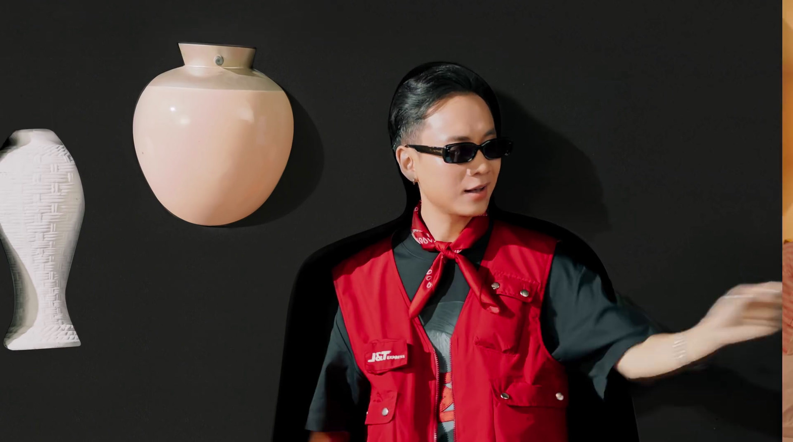 a woman standing next to a wall with a vase on it