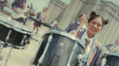 a girl in a school uniform playing drums