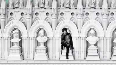 a black and white photo of a man sitting in front of statues