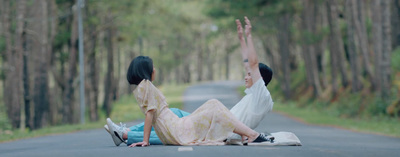 two people sitting on the side of a road