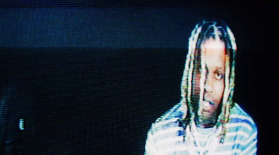 a man with dreadlocks standing in front of a tv