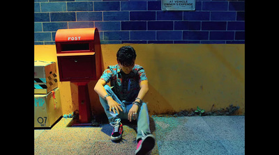 a boy sitting on the ground next to a mailbox