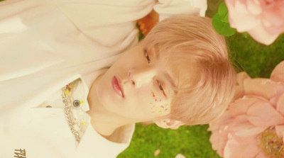 a young boy laying in the grass with flowers around him