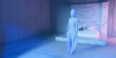 a white mannequin standing in front of a bed