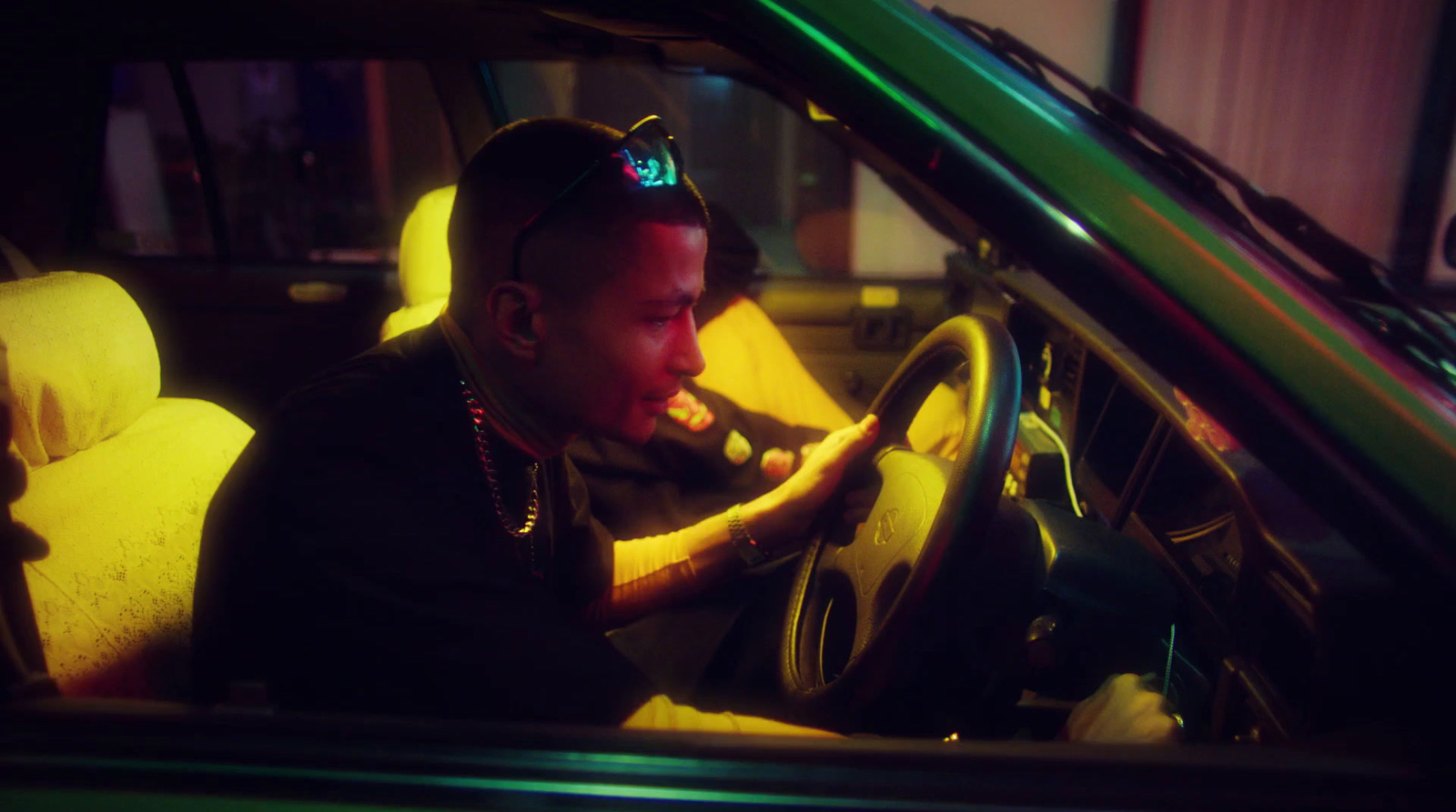 a man sitting in a car with his hand on the steering wheel