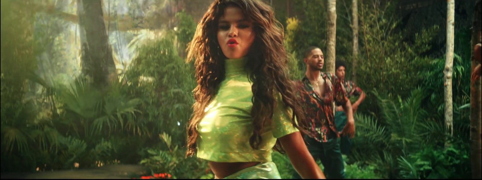 a woman in a green dress walking through a forest