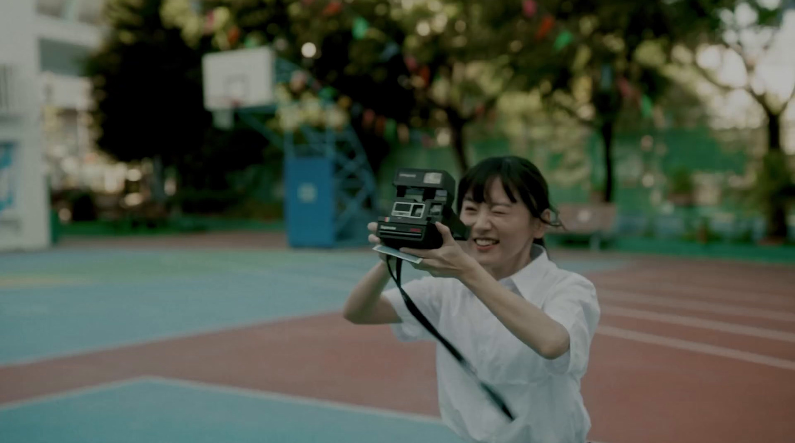 a woman taking a picture with a camera on a tennis court