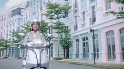 a woman riding a white scooter down a street