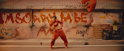 a woman in a red jumpsuit standing in front of a graffiti covered wall