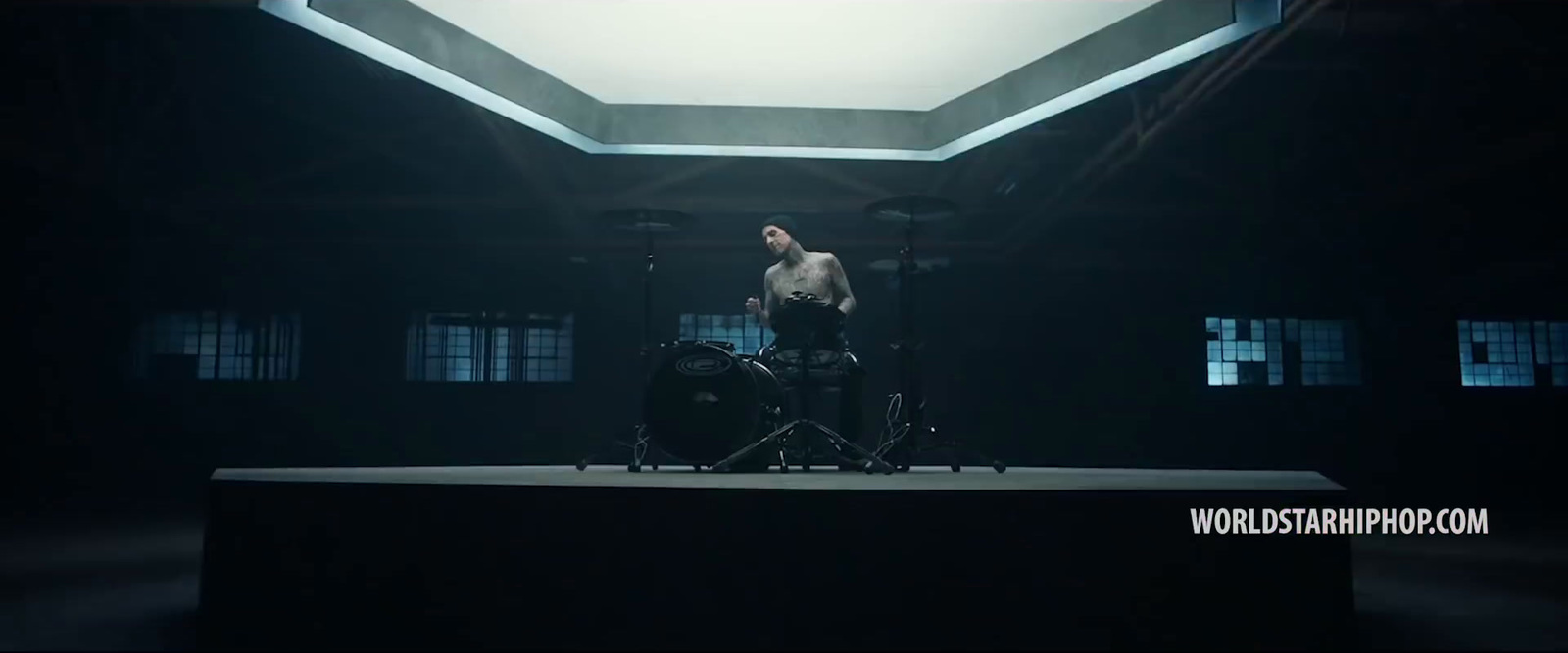 a man standing on top of a stage next to a drum set