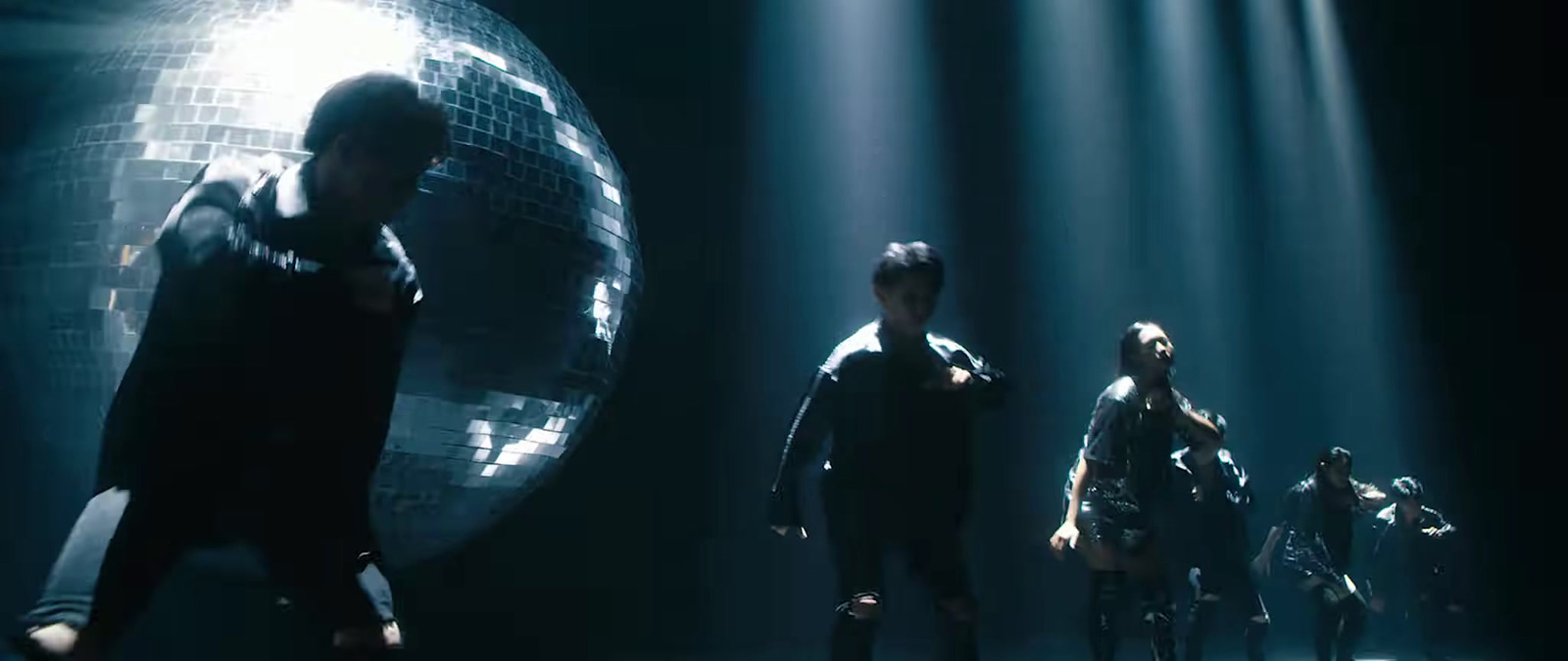 a group of people standing in front of a disco ball