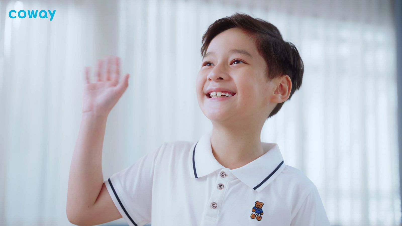 a boy in a white shirt waves to someone