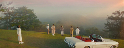 a group of people standing on top of a lush green hillside