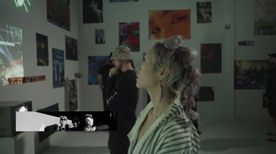 a woman standing in front of a wall with pictures on it