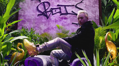 a man with white hair sitting on a purple chair