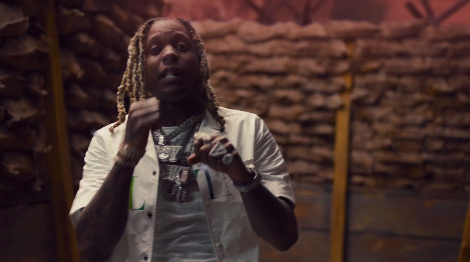 a man with dreadlocks standing in front of stacks of wood