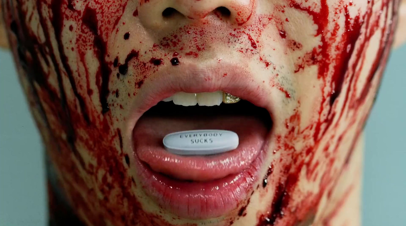 a man with blood on his face and a pill in his mouth