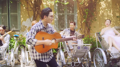 a man playing a guitar in front of a group of people