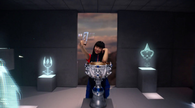 a woman holding a cell phone in front of a silver vase