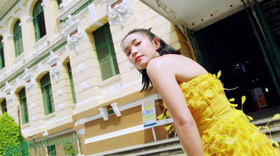 a woman in a yellow dress standing in front of a building