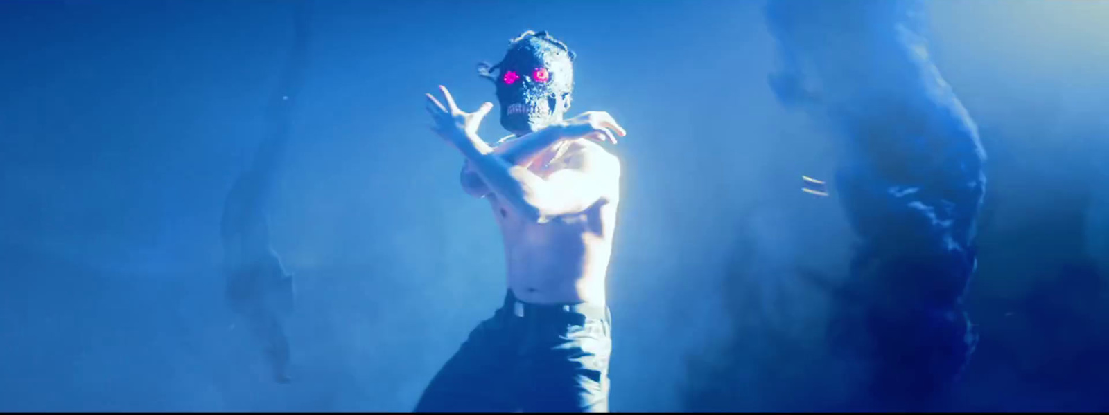 a man with a mask on standing in front of a blue background