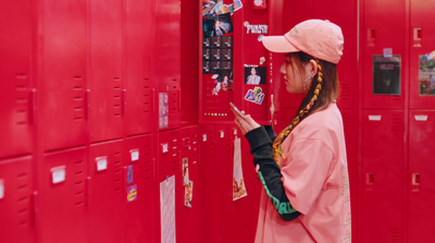 a woman in a pink hat is looking at a red locker