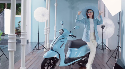 a woman standing next to a blue scooter