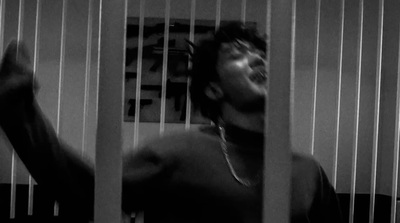 a man standing behind bars in a jail cell