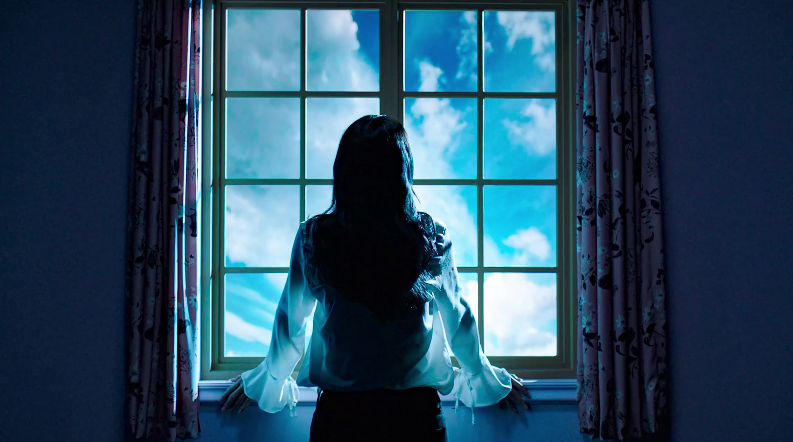 a woman standing in front of a window in a dark room