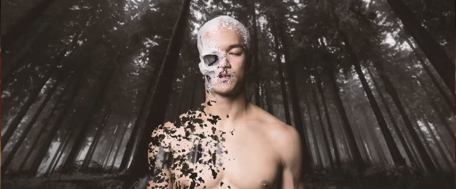 a shirtless man standing in a forest covered in black and white paint