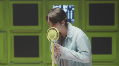 a woman holding a yellow blow dryer next to a green wall