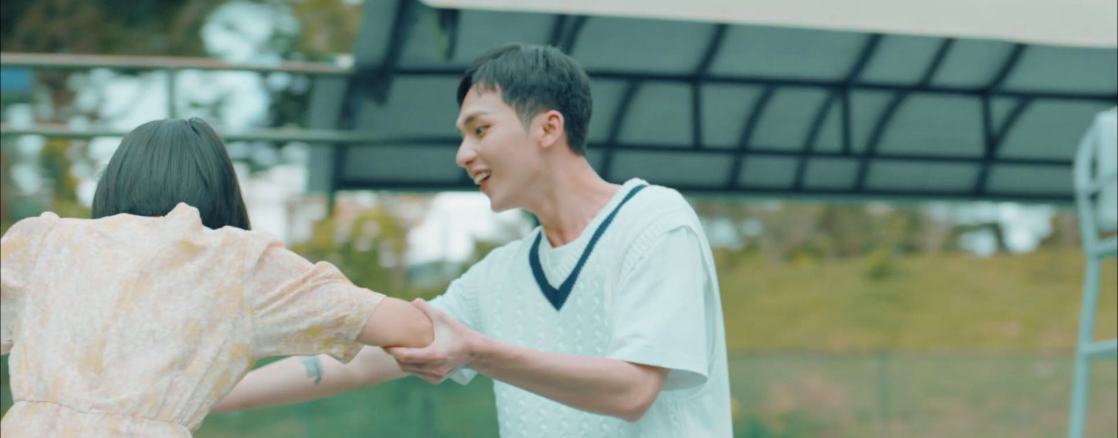 a man holding a woman's hand in front of a tennis court