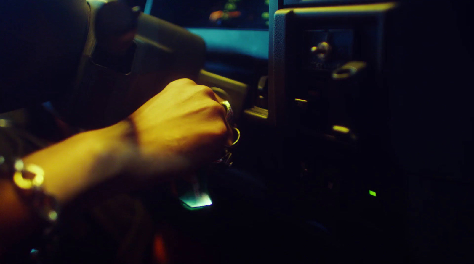 a person driving a car at night with their hand on the steering wheel