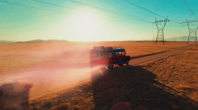 a truck driving down a dirt road next to power lines