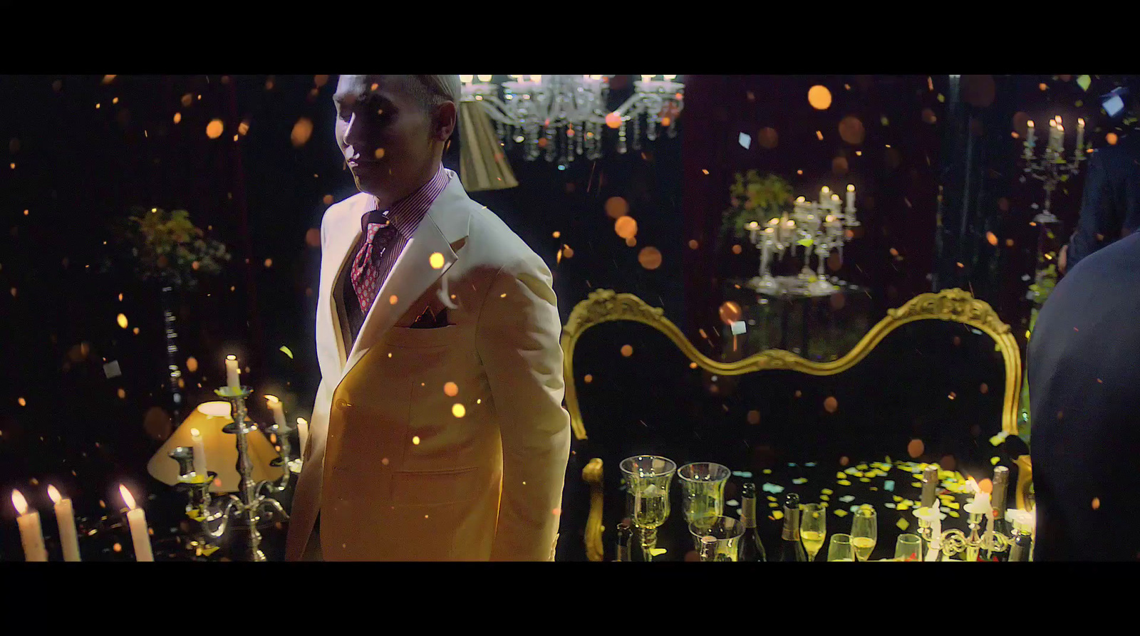 a man in a suit and tie standing in front of a table with candles