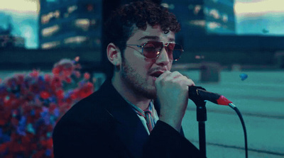 a man in a suit and sunglasses singing into a microphone