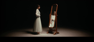 a woman standing next to a mirror in the dark