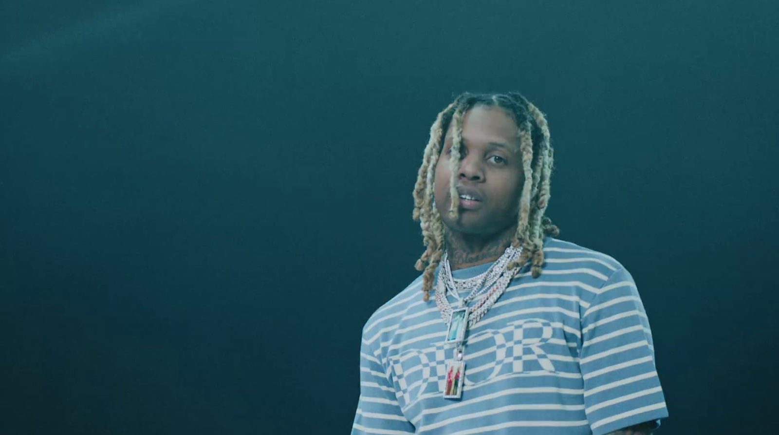 a man with dreadlocks standing in front of a black background