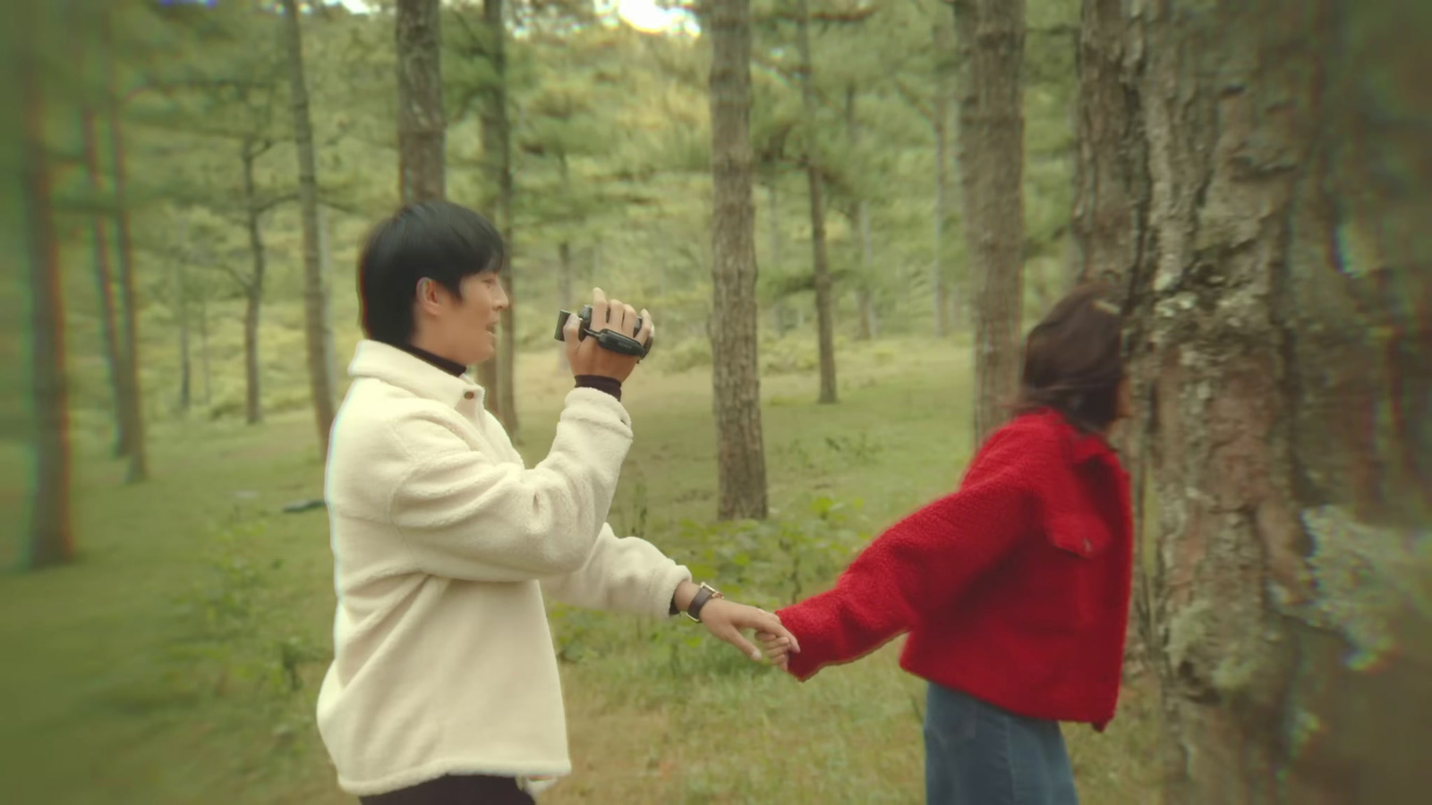 a man and a woman holding hands in the woods