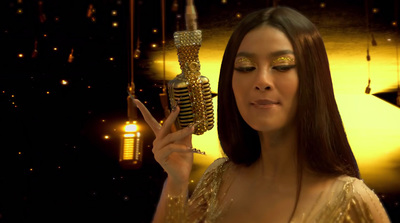 a woman in a gold dress holding a microphone