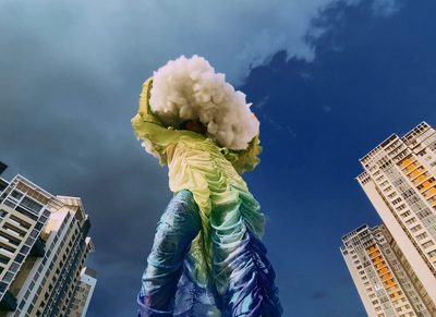 a person with a large cloud on their head in front of tall buildings