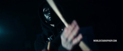 a person in a black hoodie holding a wooden stick