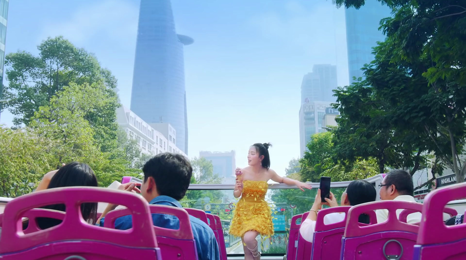 a woman in a yellow dress riding on a pink bus