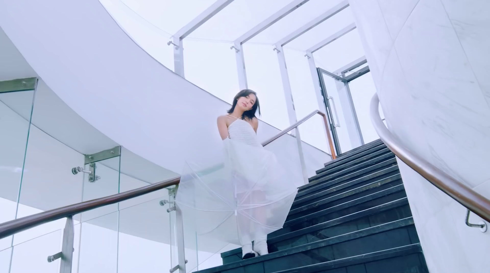 a woman in a white dress is walking down a set of stairs